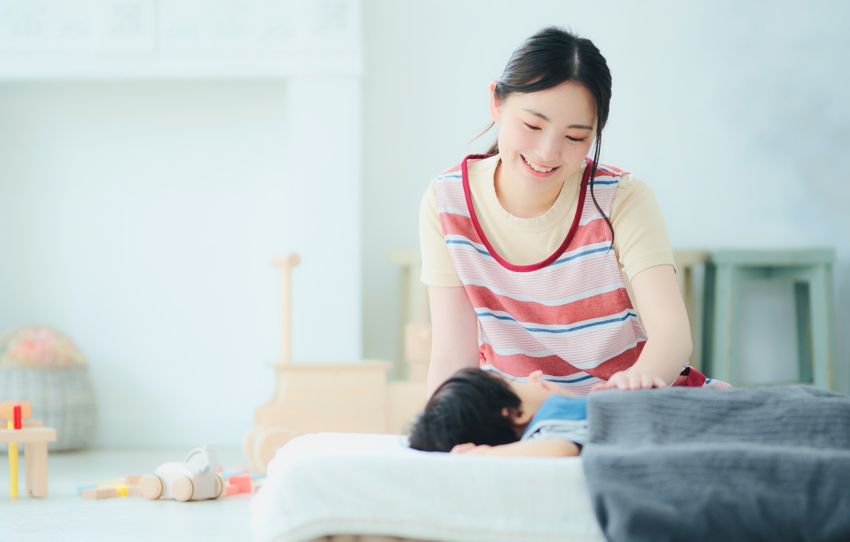 保育士と昼寝する子供